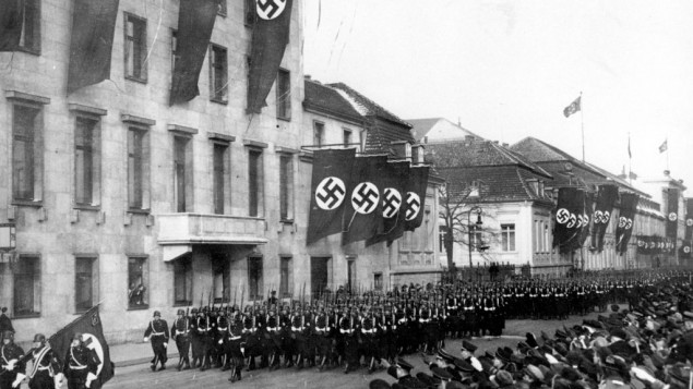 An Associated Press photograph shows a parade of Nazi black guards marching past the Reich Chancellory on Wilhelmstrasse during their parade in Berlin, Germany, on Jan. 30, 1937.