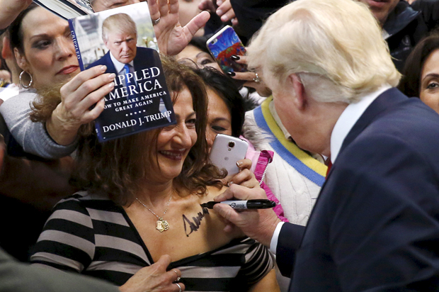 Republican presidential candidate Donald Trump (R) autographs the chest of a woman at his campaign rally in Manassas, Virginia December 2, 2015.